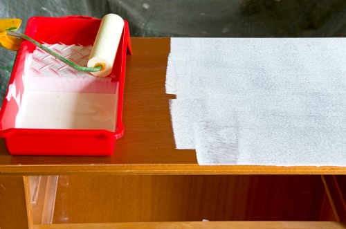 paint roller with white paint and a commode