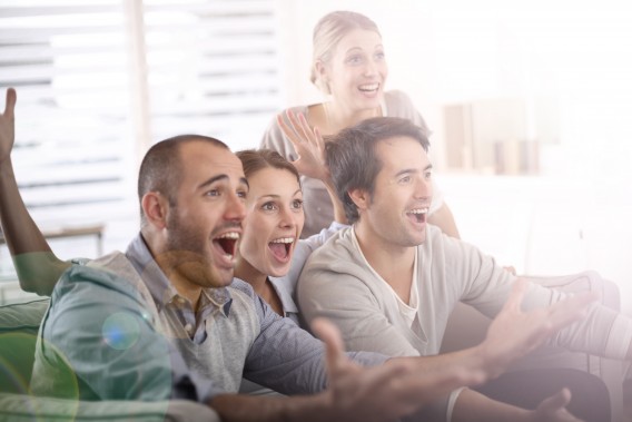 Cheerful group of friends watching football game on tv