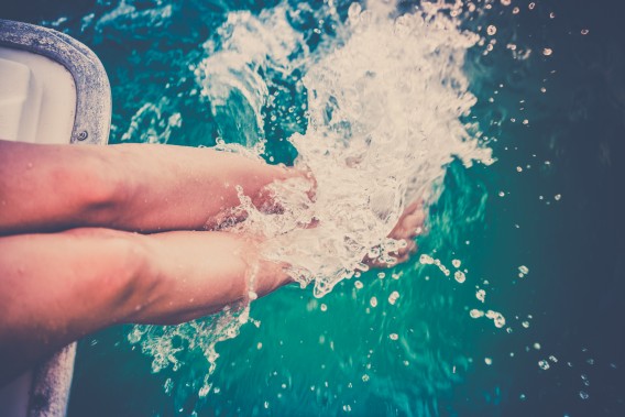 Female legs splashing sea water from a sailing yacht