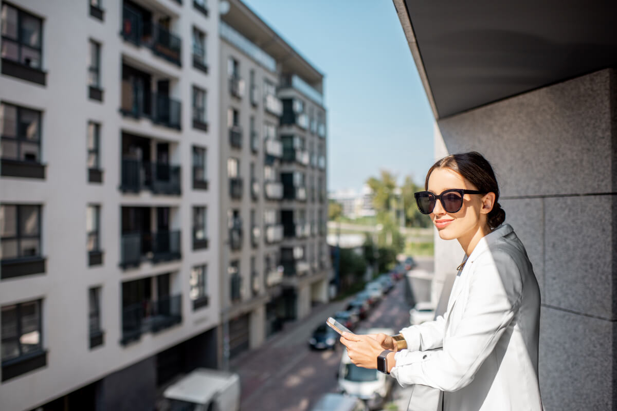 Woman stands on apartment balcony.